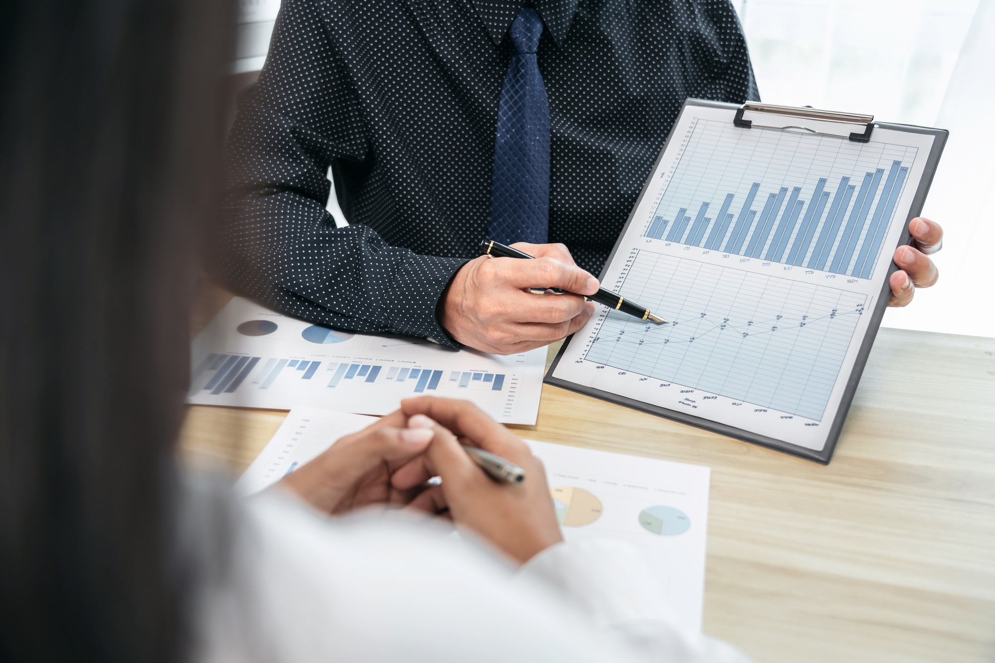 A man and a woman are looking at a chart on a table