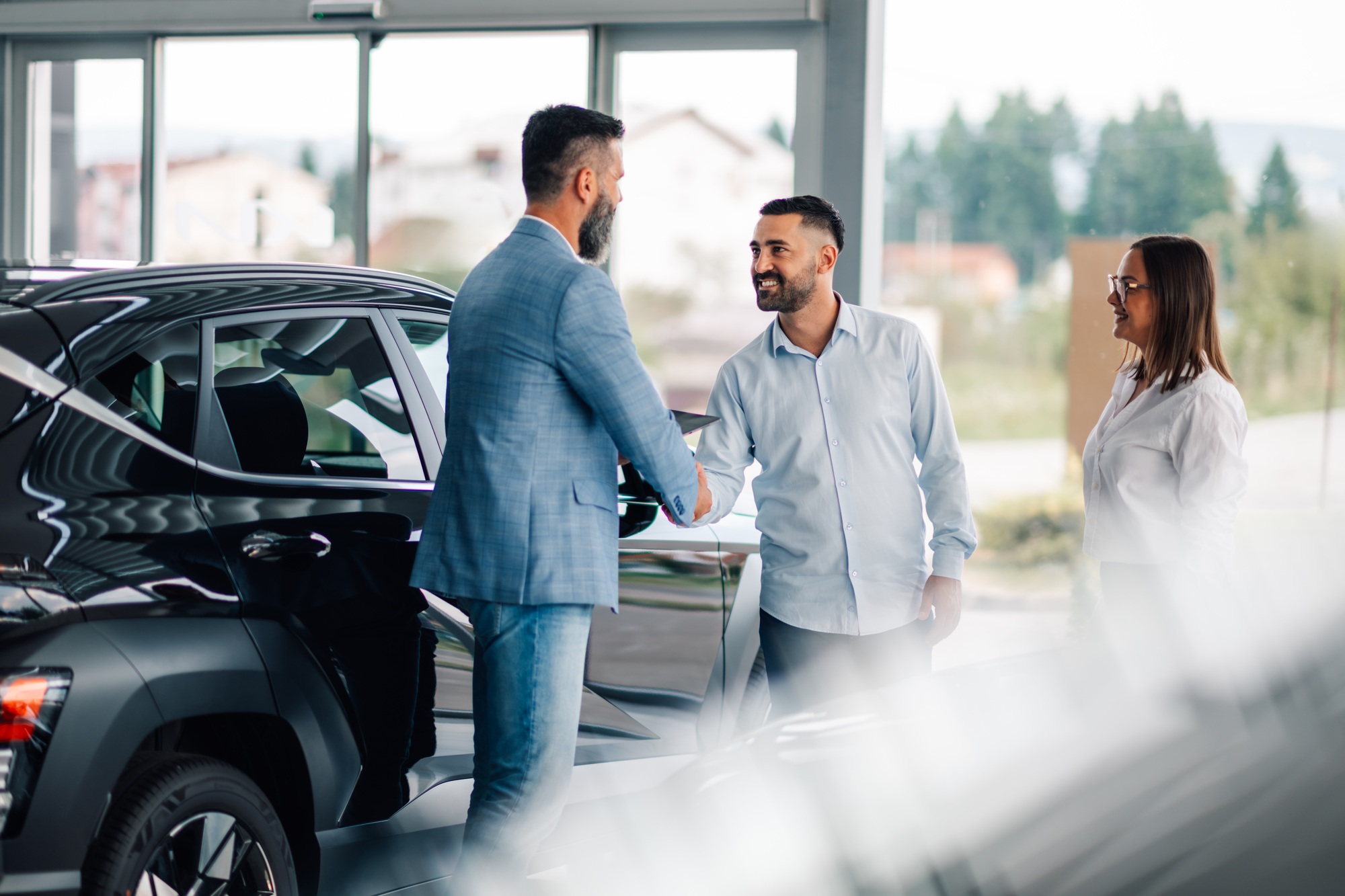 Car dealership handshake marking successful negotiation agreement.